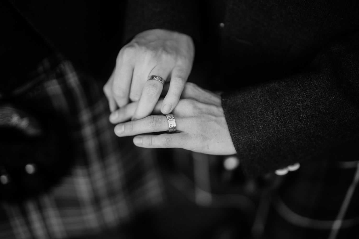 Close-up black and white detail shot of hands during a wedding celebration.