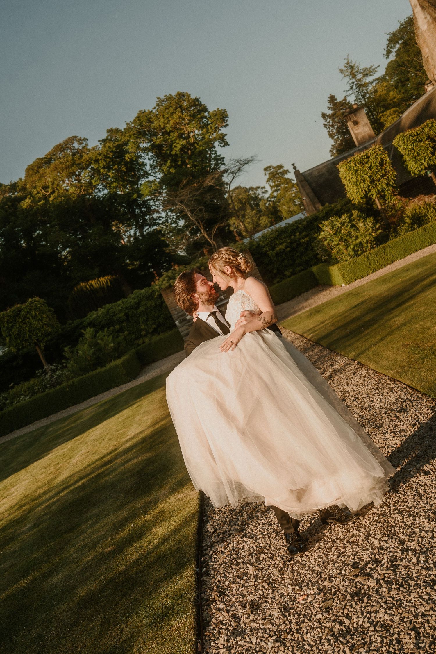 Couple walking together on gravel path during golden hour wedding photoshoot.
