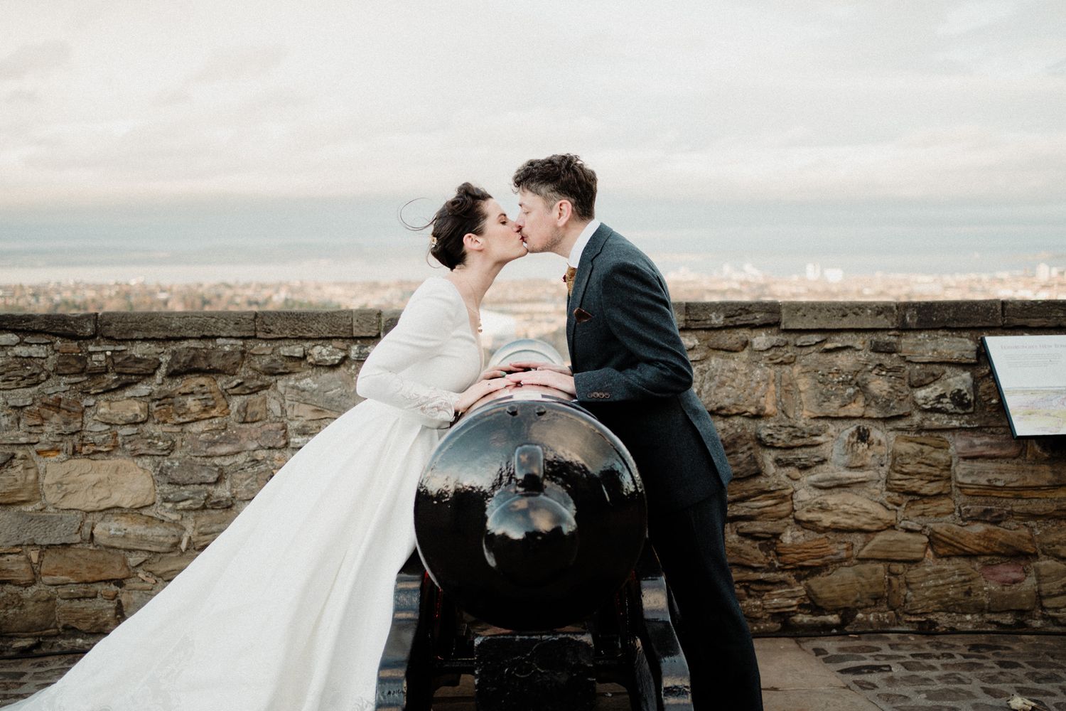 Romantic kiss shared beside historic cannon on castle fortification.