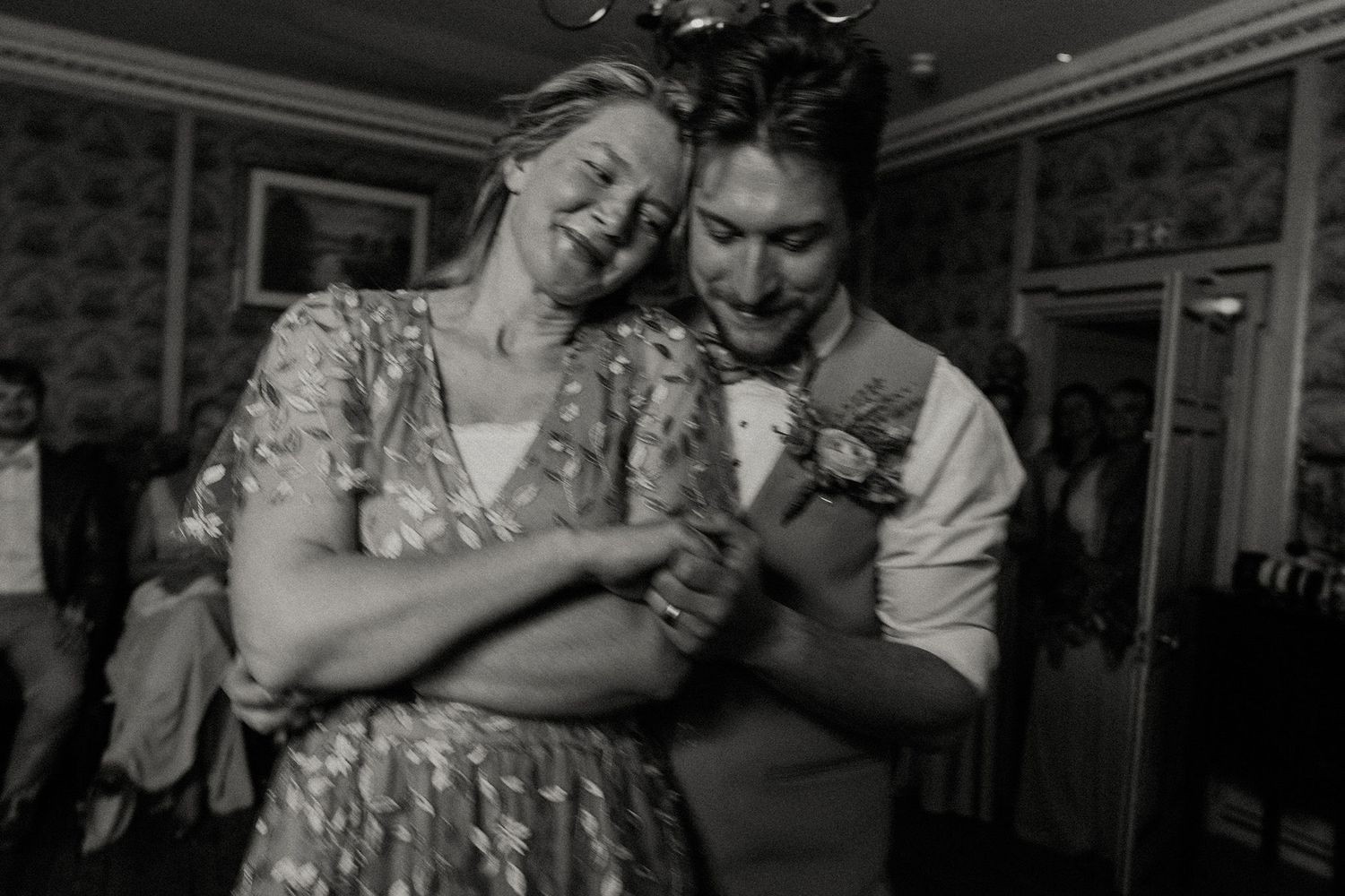 Black and white photo of a laughing couple dancing together at a wedding reception.