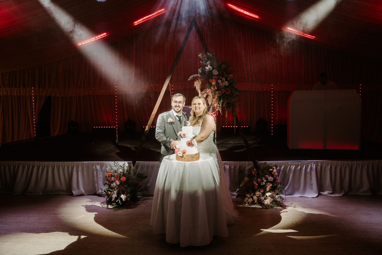 Romantic first dance at wedding reception with dramatic red lighting and white spotlights.
