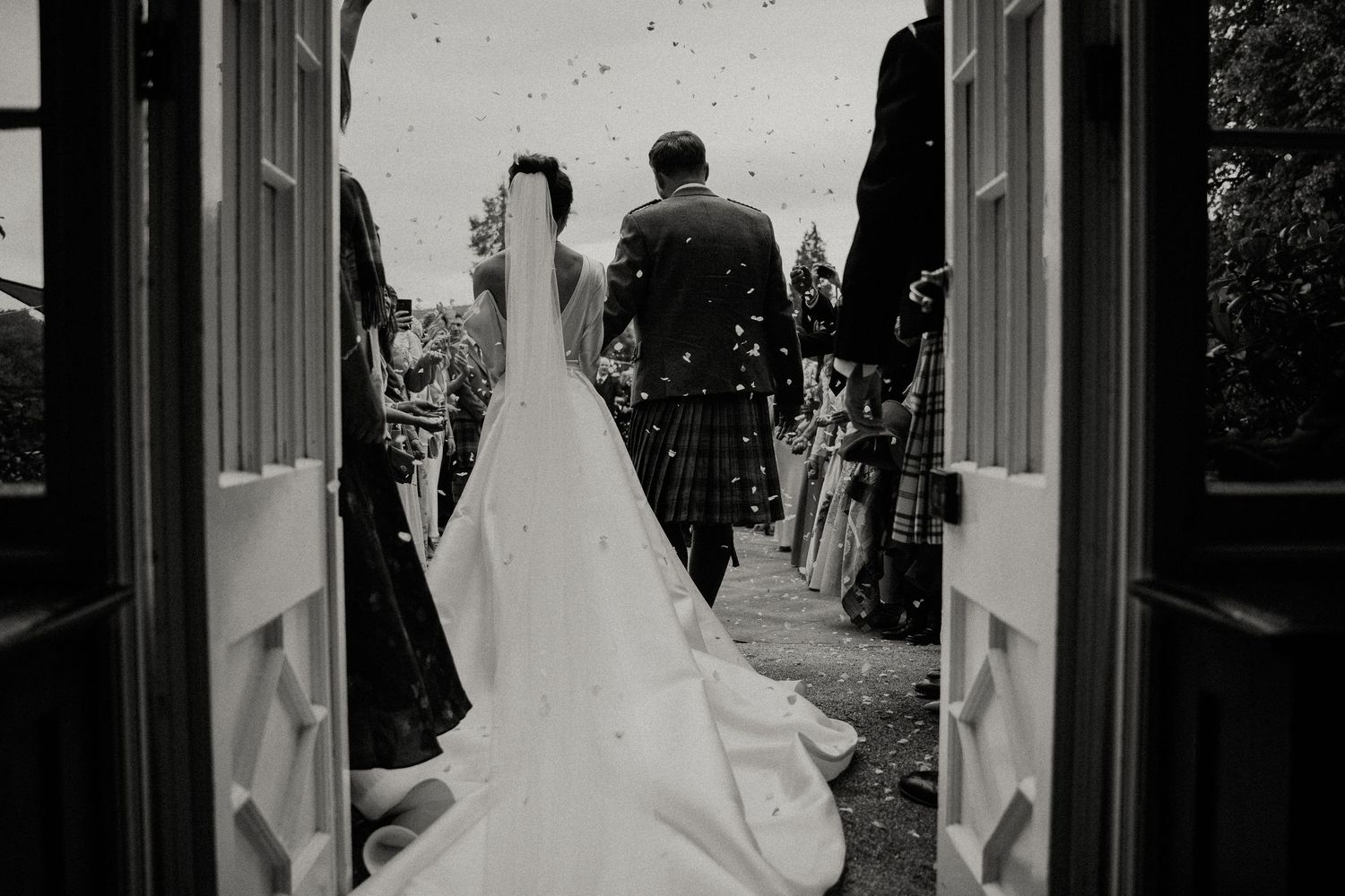 Wedding ceremony moments captured in black and white through a window frame.
