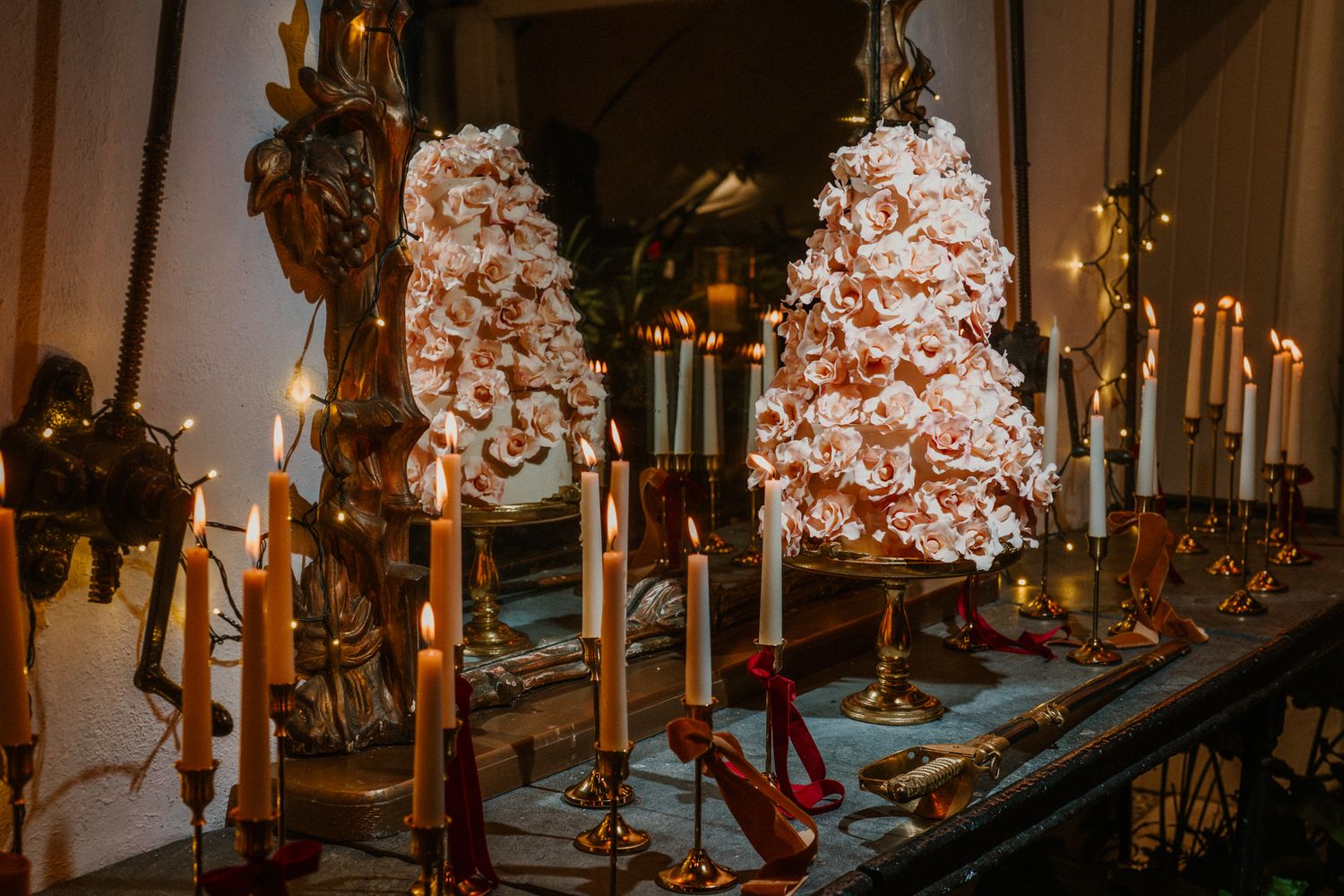Candlelit dinner table with ornate gold frames and floral arrangements creating an elegant atmosphere.