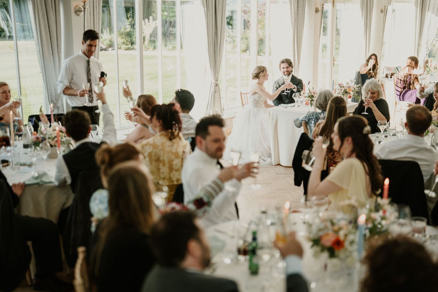 Wedding guests celebrating and applauding during reception dinner.