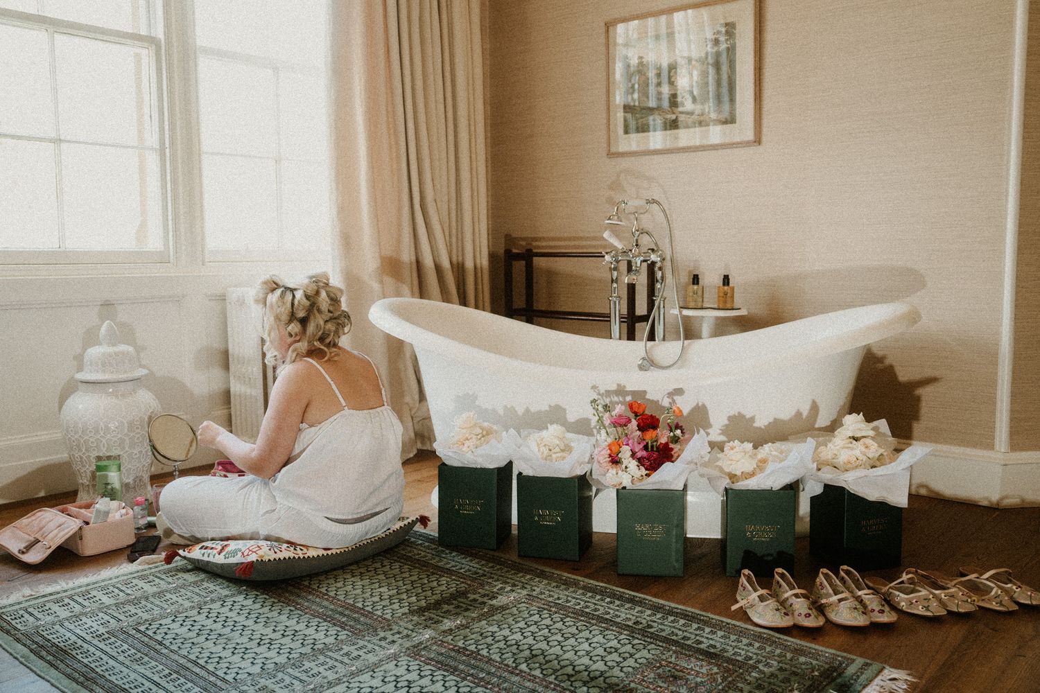 Elegant clawfoot bathtub surrounded by wedding details and decor in a soft-lit room.