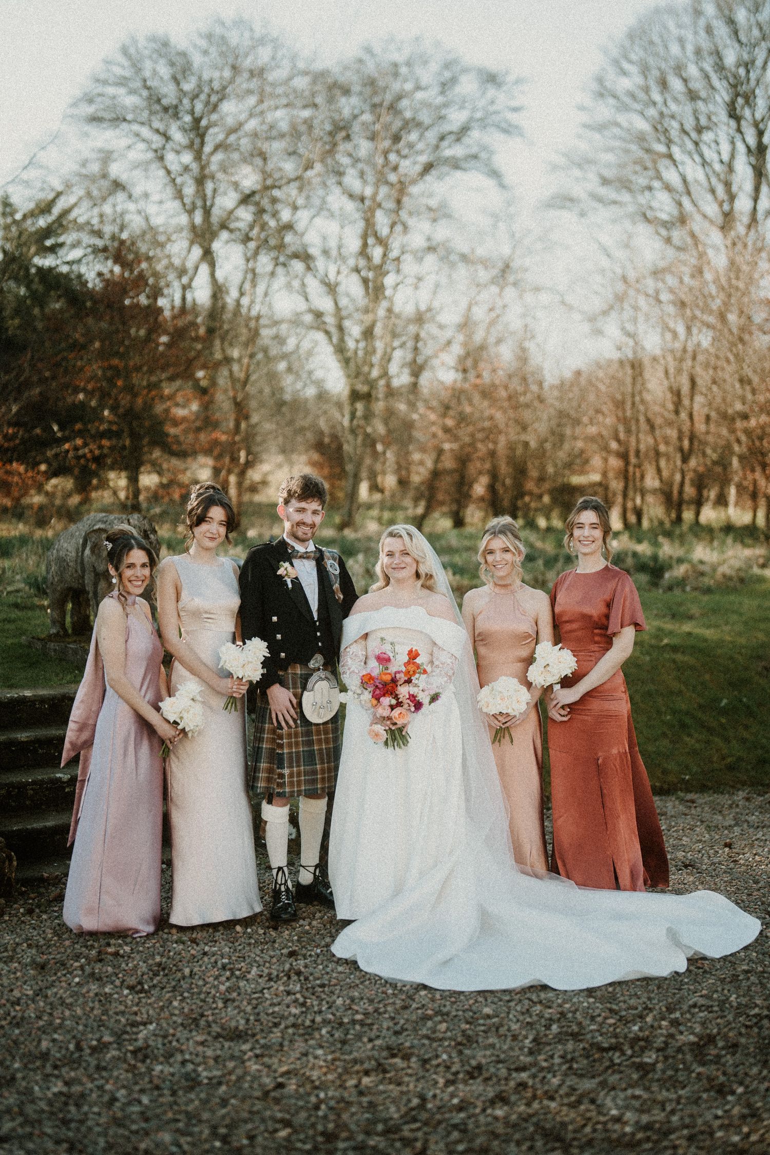 Bridal party members in coordinated dresses gather for outdoor photos.