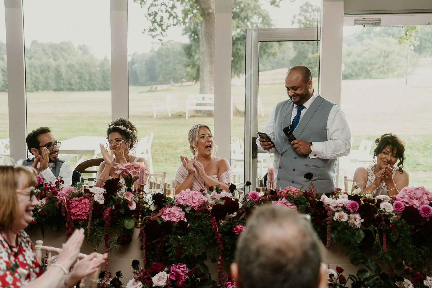 Wedding reception dinner setup with pink floral arrangements and outdoor views.