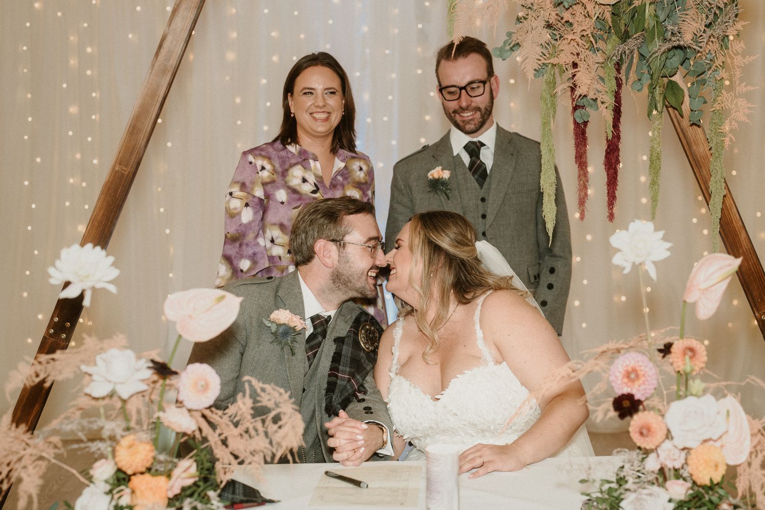 Wedding reception decor featuring string lights, floral arrangements and romantic lighting.