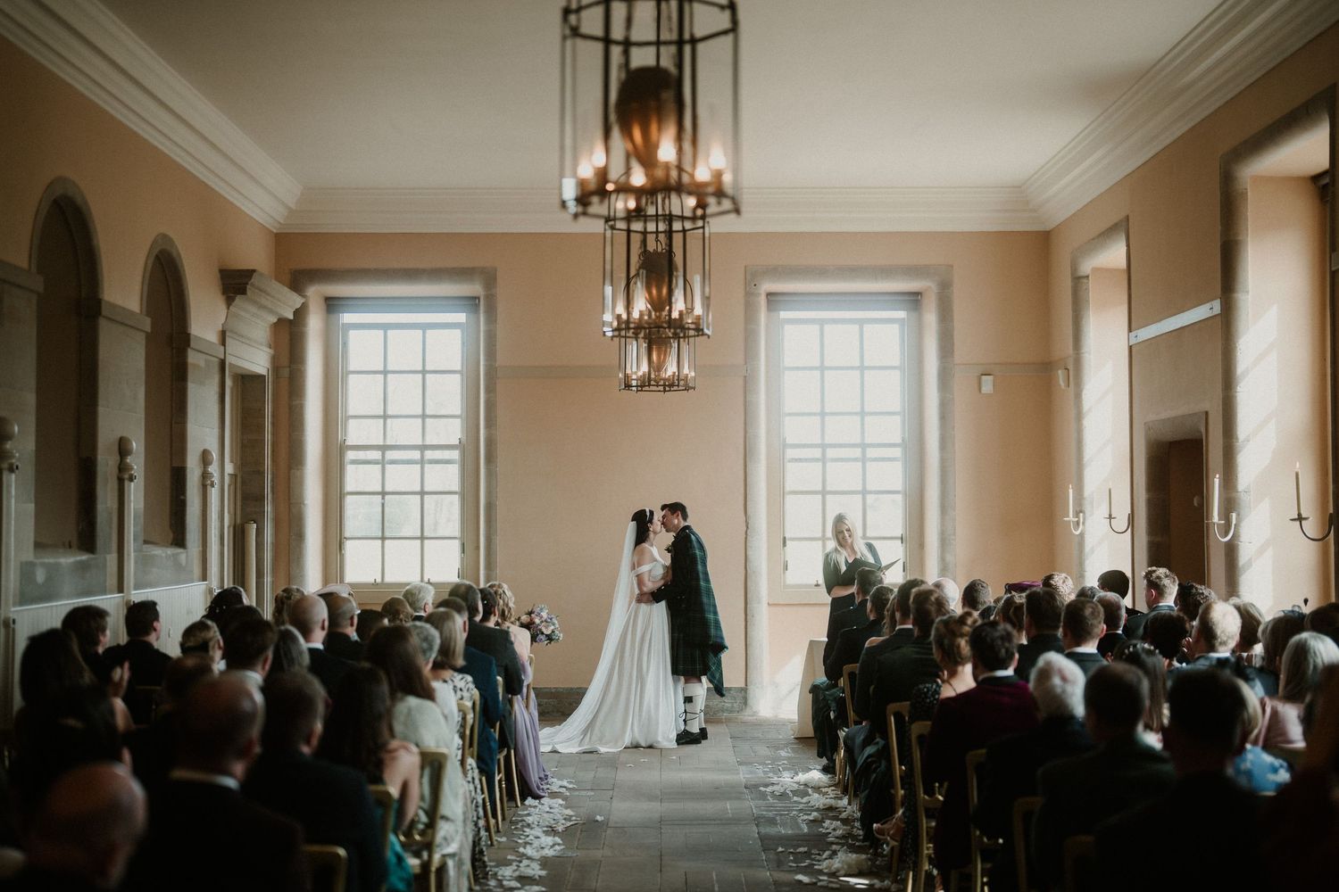 Elegant wedding ceremony venue with cream walls, chandeliers and large windows.