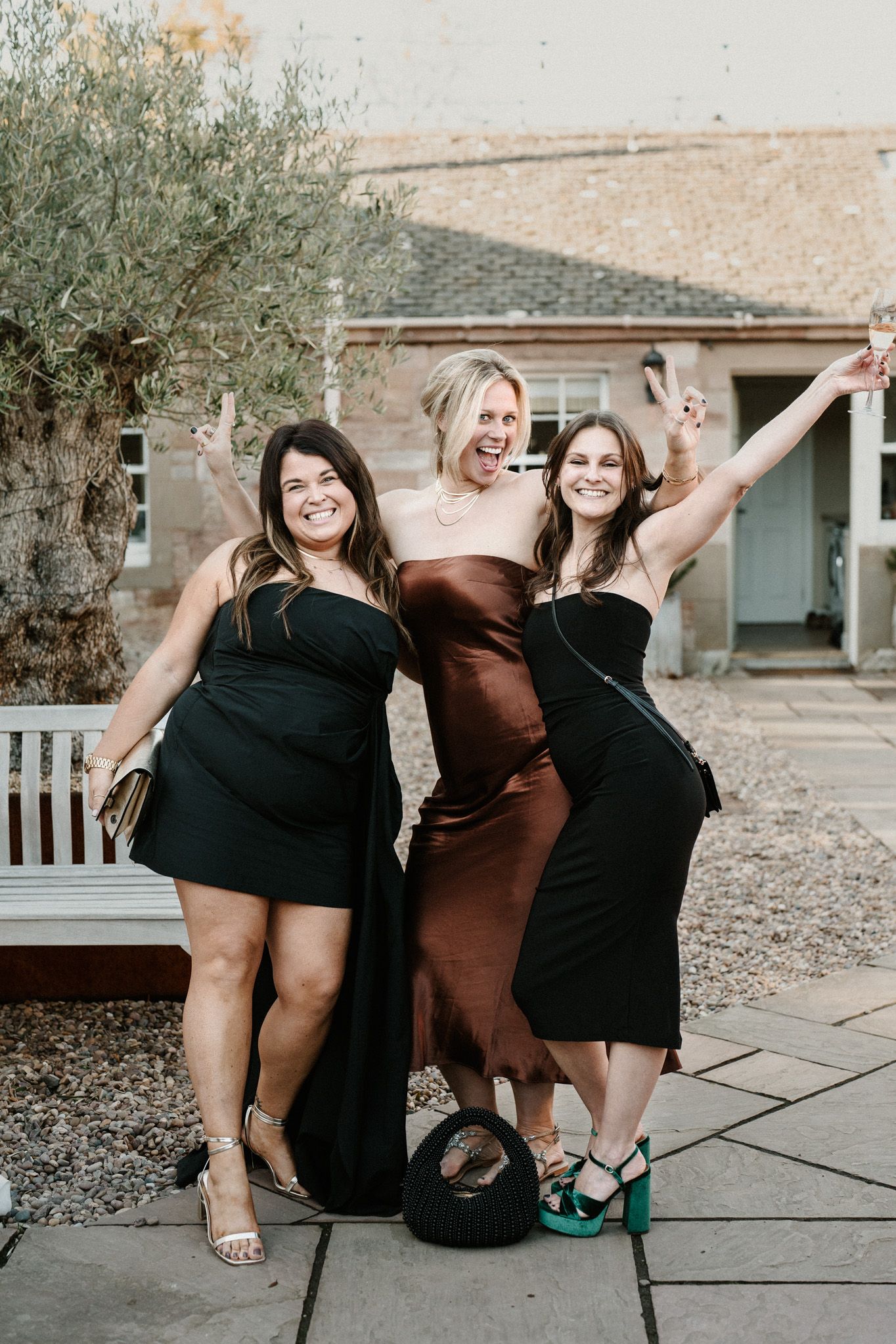 Group of friends in formal attire posing playfully on stone steps.