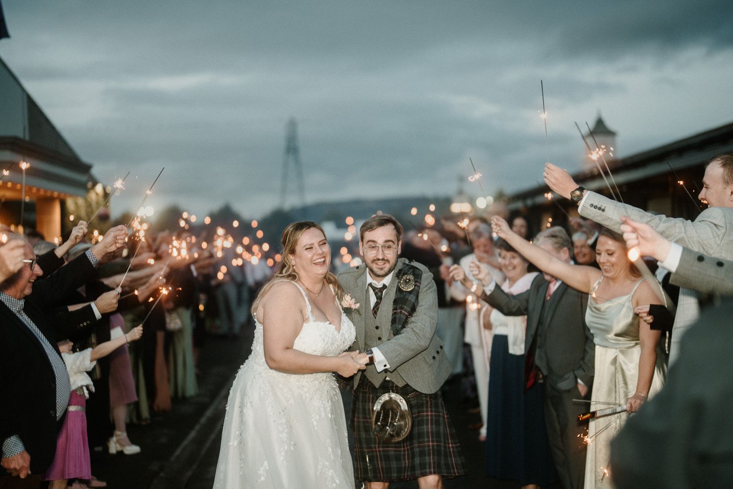 Newlyweds walk through a tunnel of guests throwing confetti during their wedding exit.