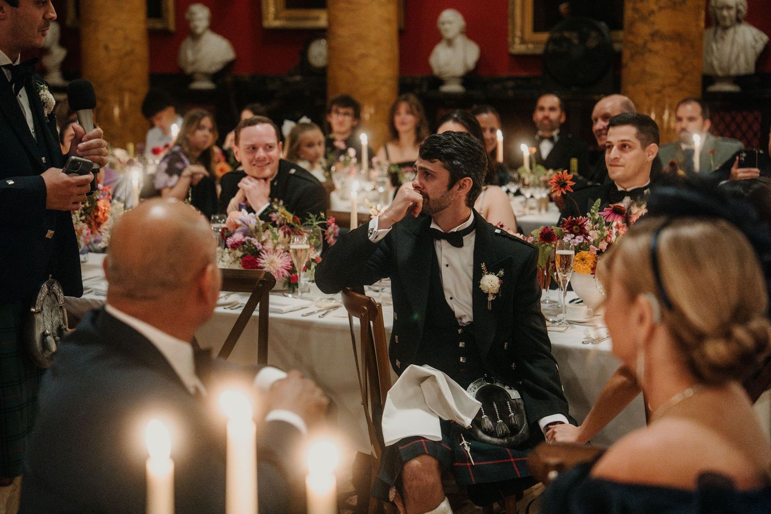 Candlelit wedding reception dinner in an elegant ballroom with ornate decor.