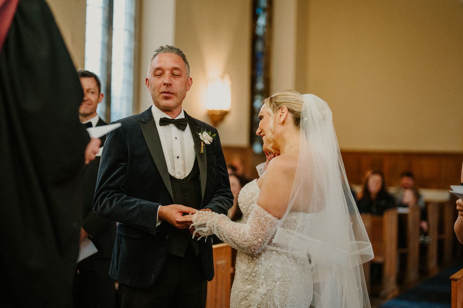 A couple participates in their wedding ceremony inside a warmly lit church.