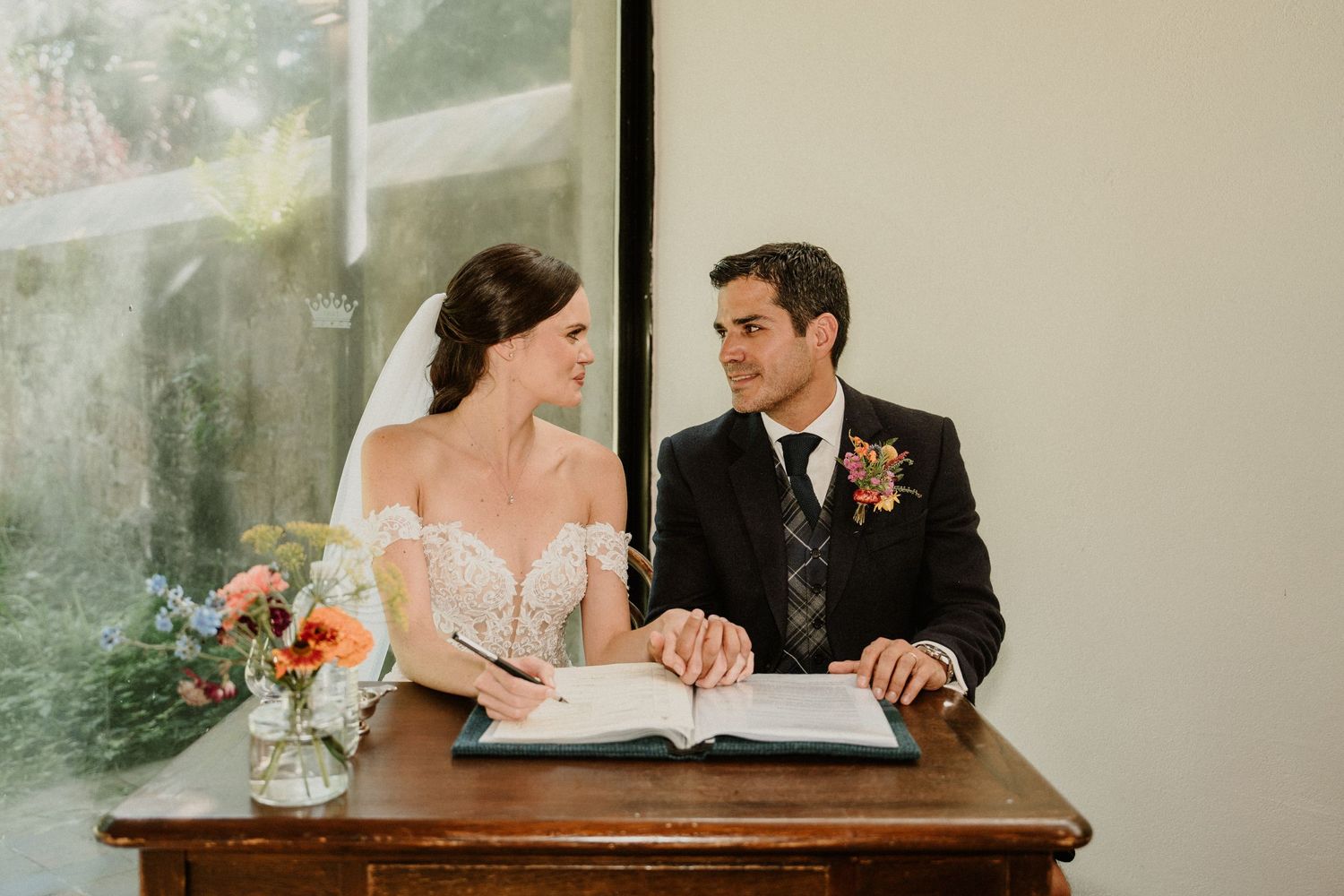 Close-up view of wedding document signing at a wooden table.