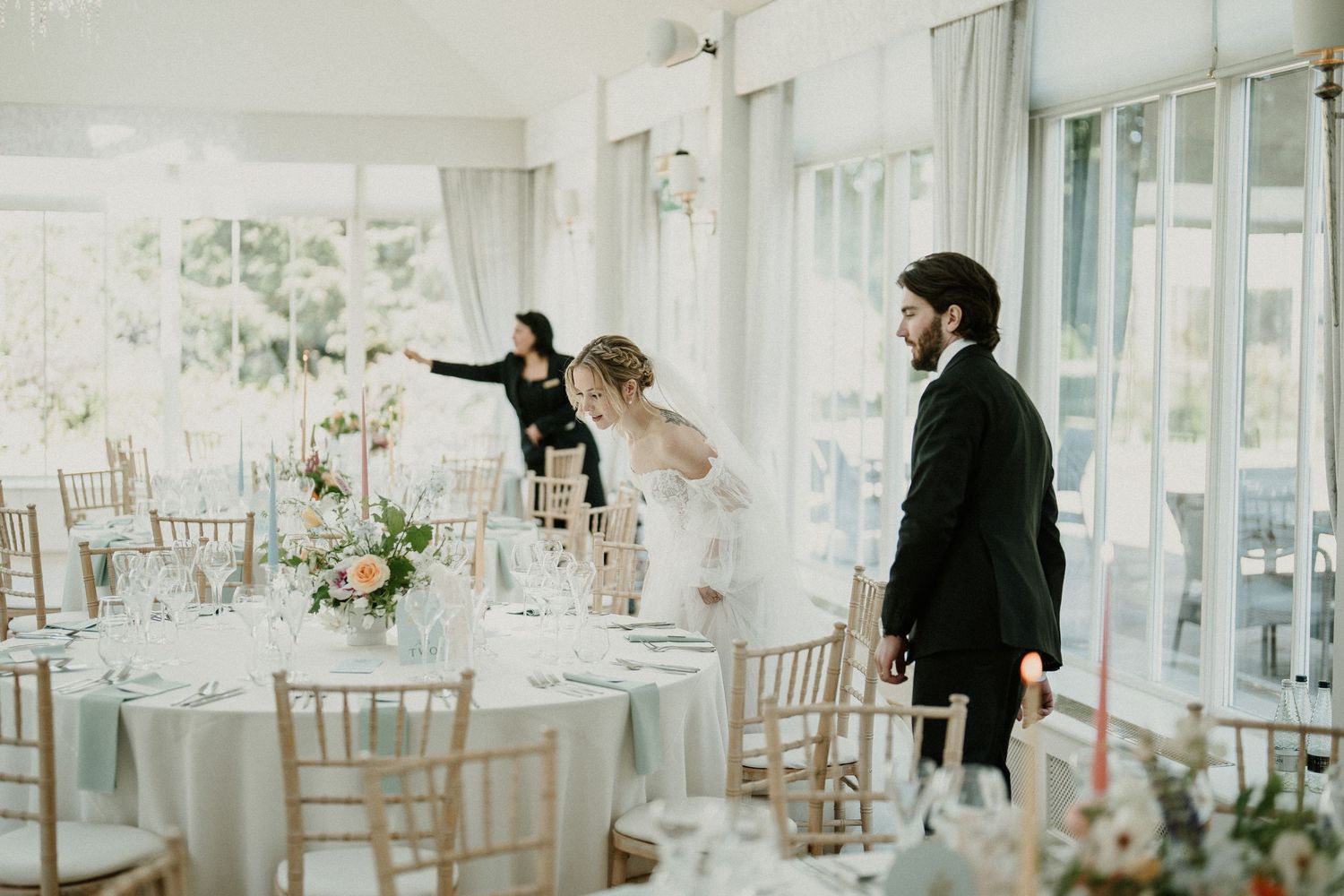 Elegant wedding reception venue with white tables, chiavari chairs, and floral centerpieces.