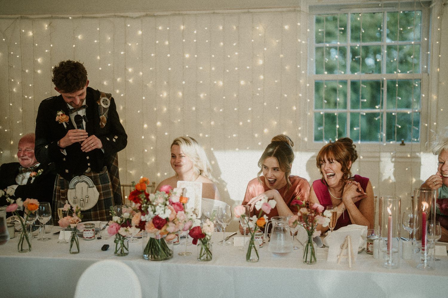 Elegant wedding reception space with twinkle light backdrop and floral centerpieces.