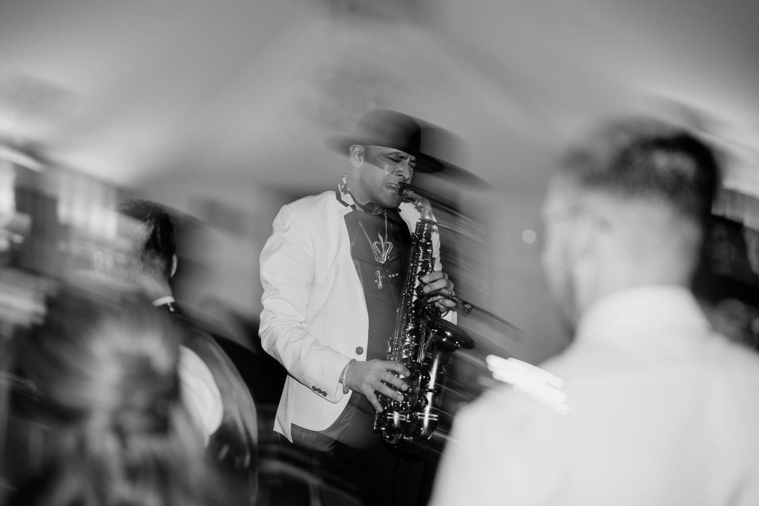 Black and white motion blur photo of wedding guests dancing at a reception.