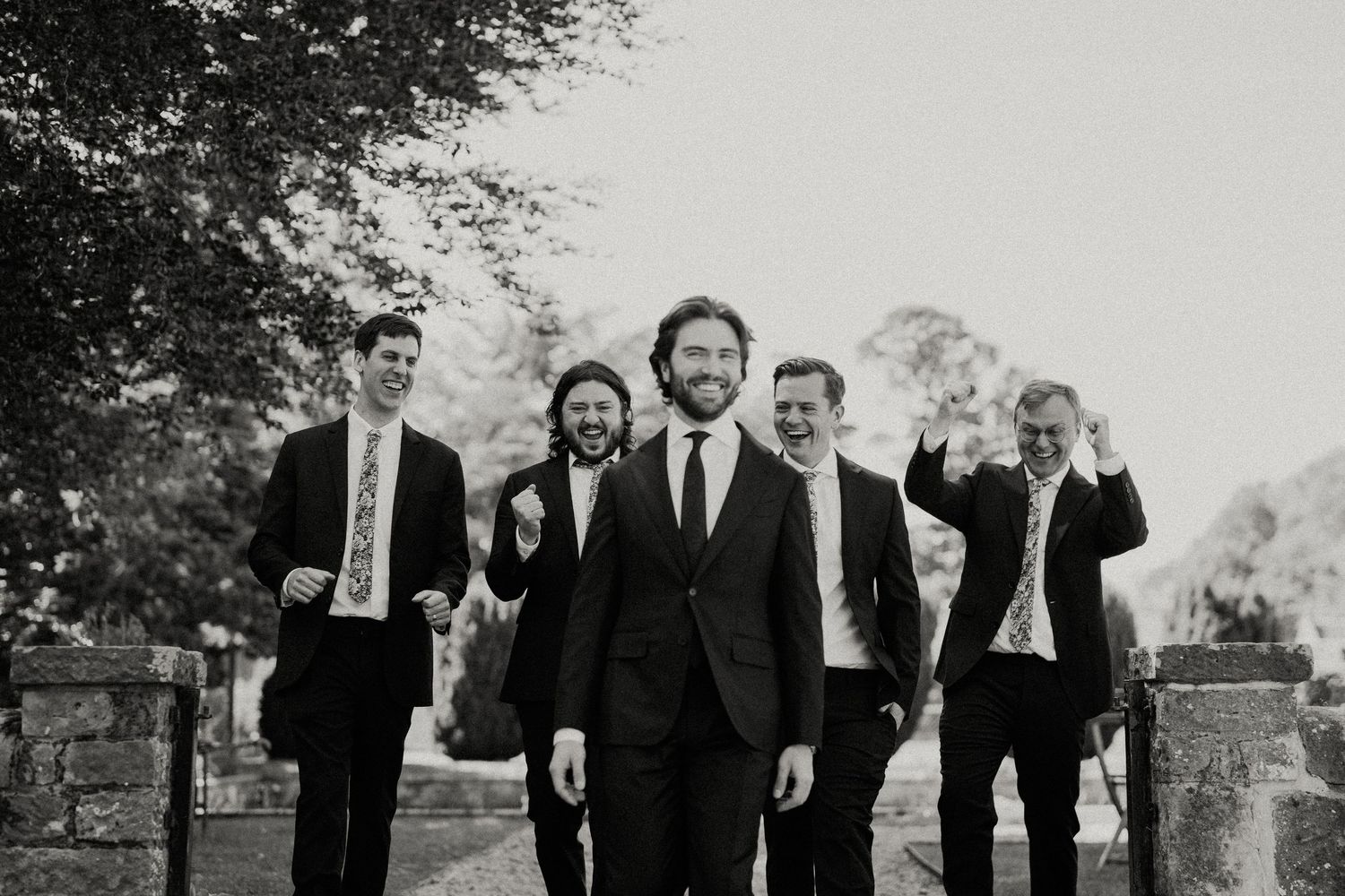 Black and white photo of wedding party members walking together outdoors.