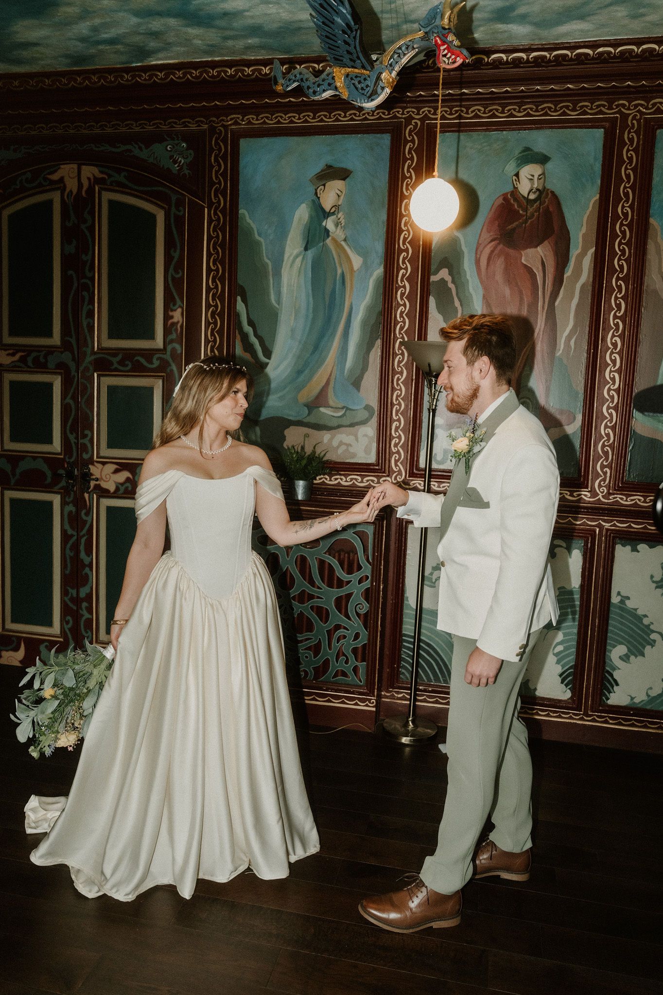 Bride and groom share a romantic dance in an ornate room with colorful murals and vintage decor on their wedding day.