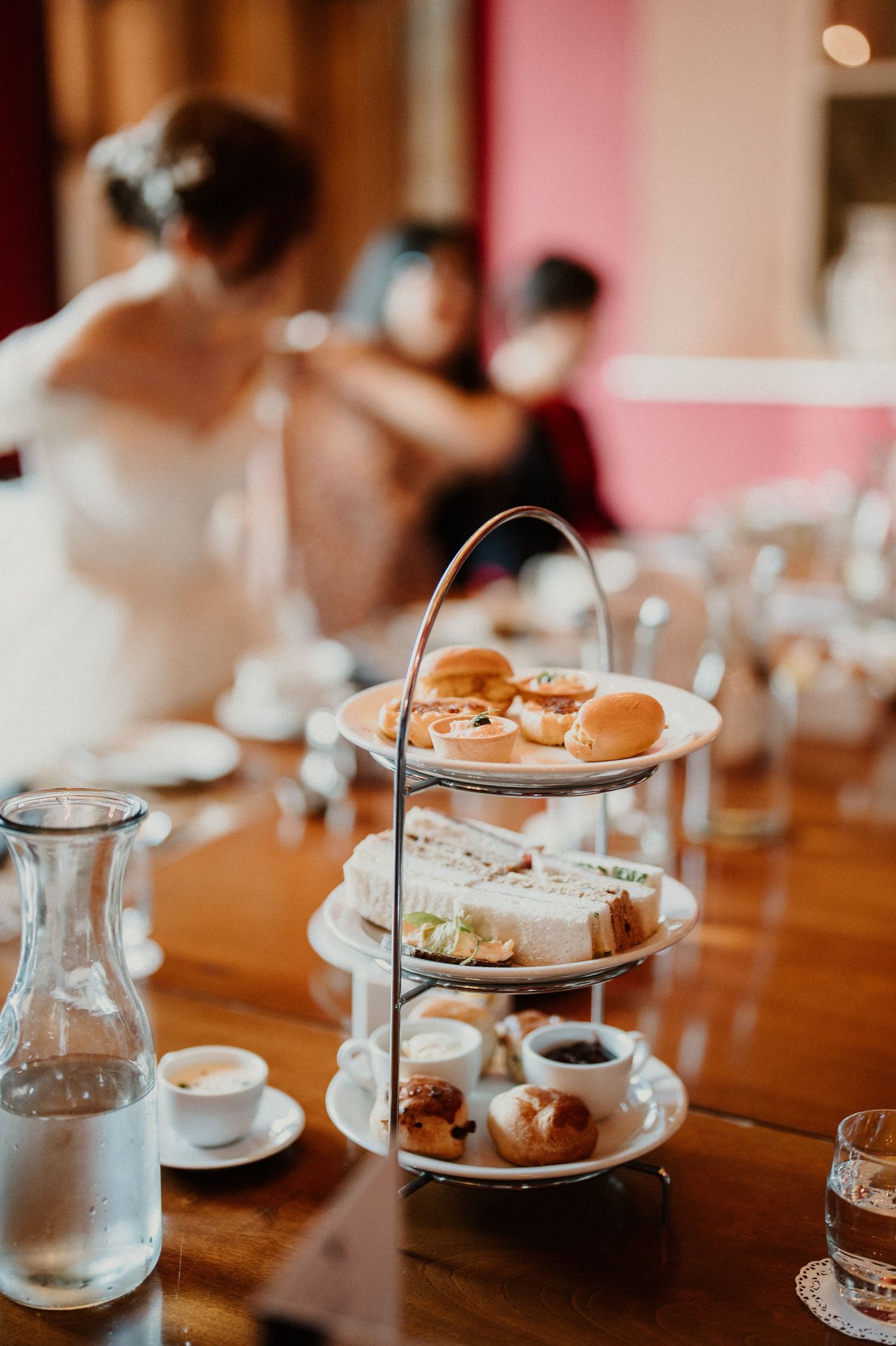 Tea service and pastries arranged on wooden table at wedding reception.