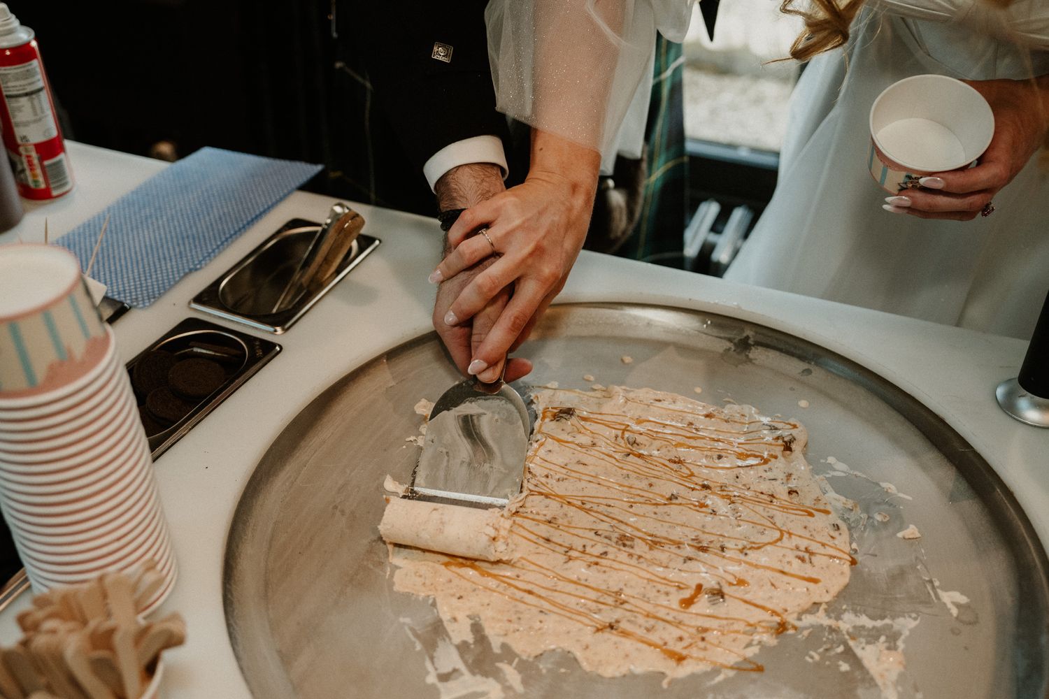 Close-up of hands preparing food on a large silver platter at a catering station.