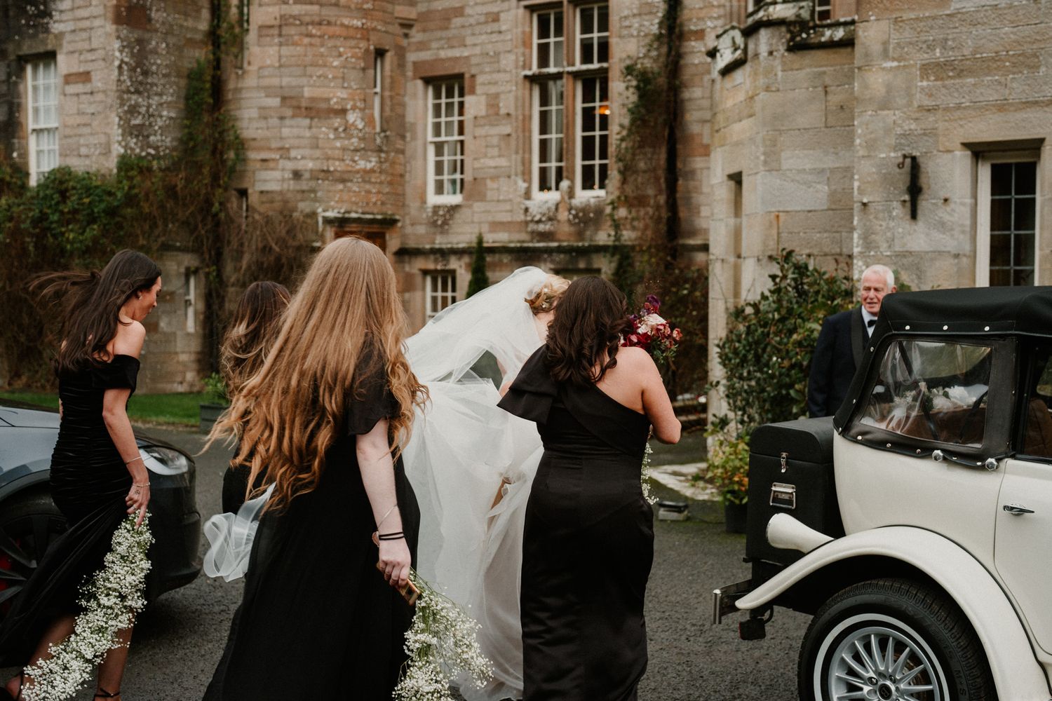 Wedding party walking together outside a classic stone building.