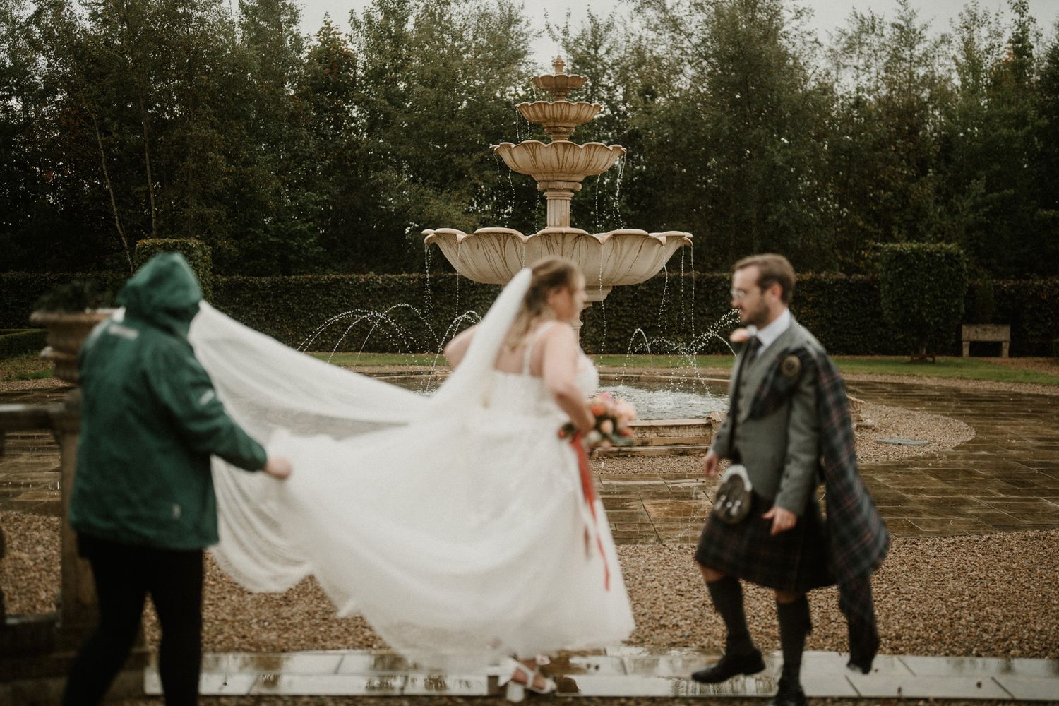 Newlyweds stroll along a tree-lined pathway with flowing white dress in motion.