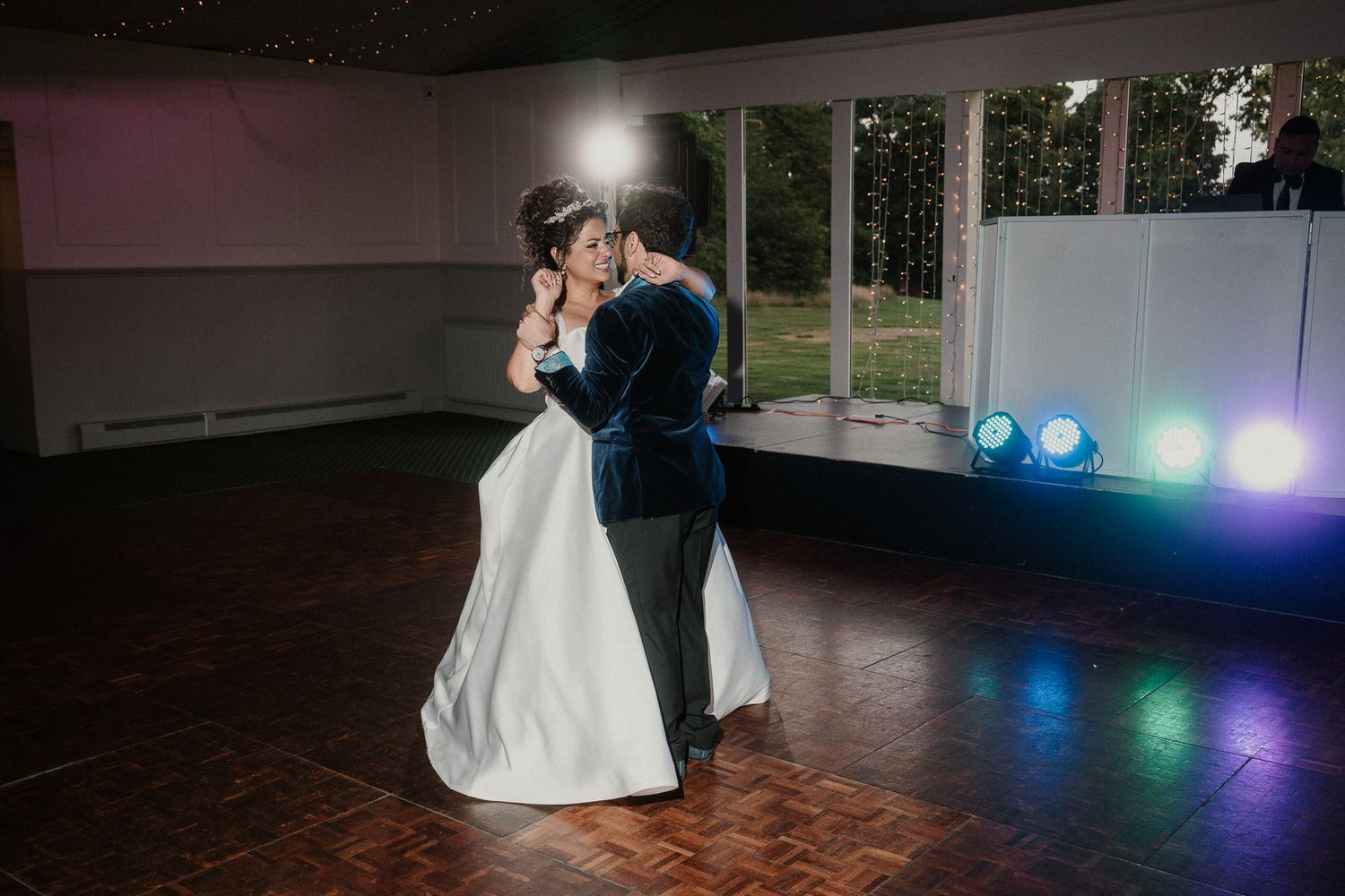 A couple shares their first dance in an elegantly lit reception room.