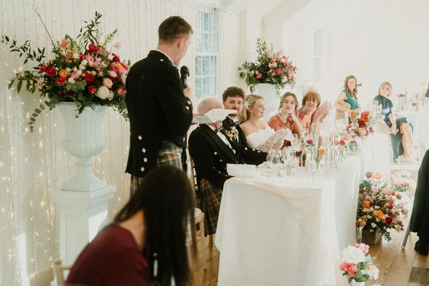 Wedding reception hall with elegant table settings and coral floral arrangements.