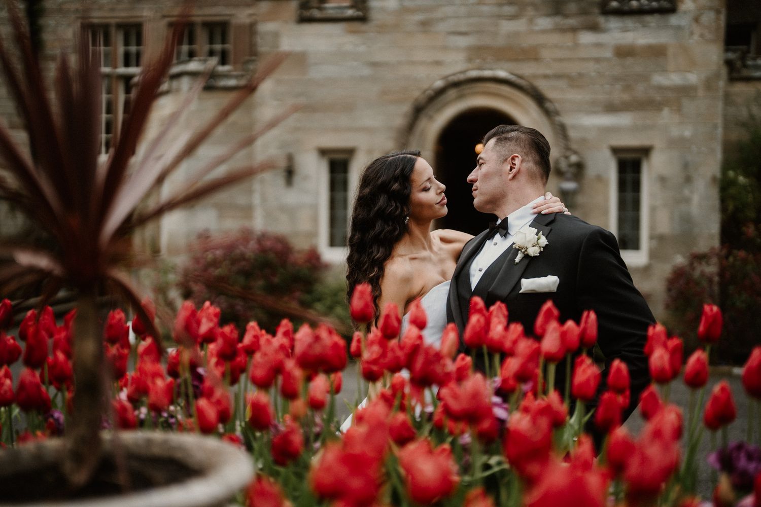Stone building facade with vibrant red tulips in foreground during wedding celebration.