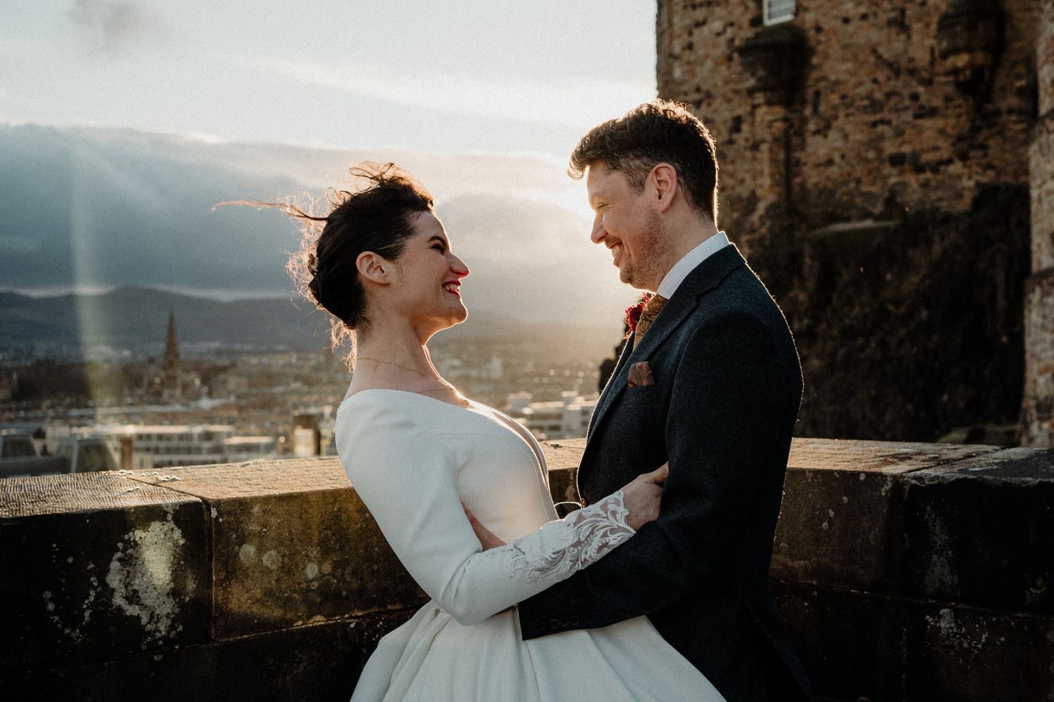 Romantic sunset wedding portrait against a stone castle backdrop.