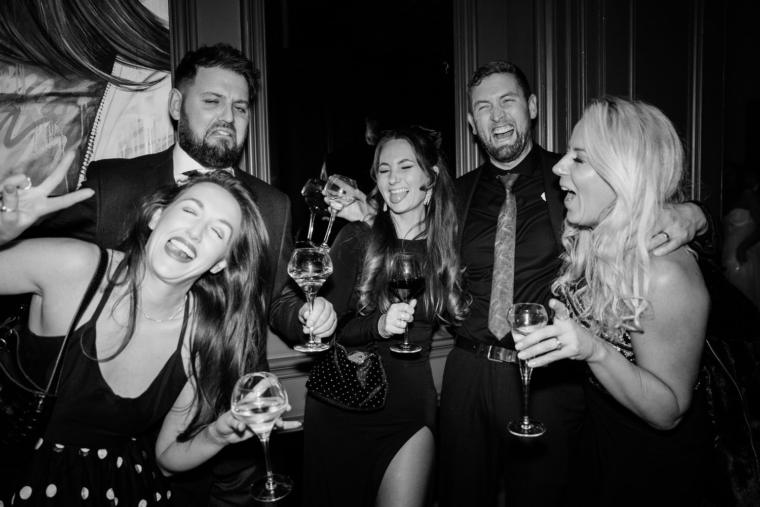 Black and white candid photos of wedding guests laughing and celebrating at a reception.