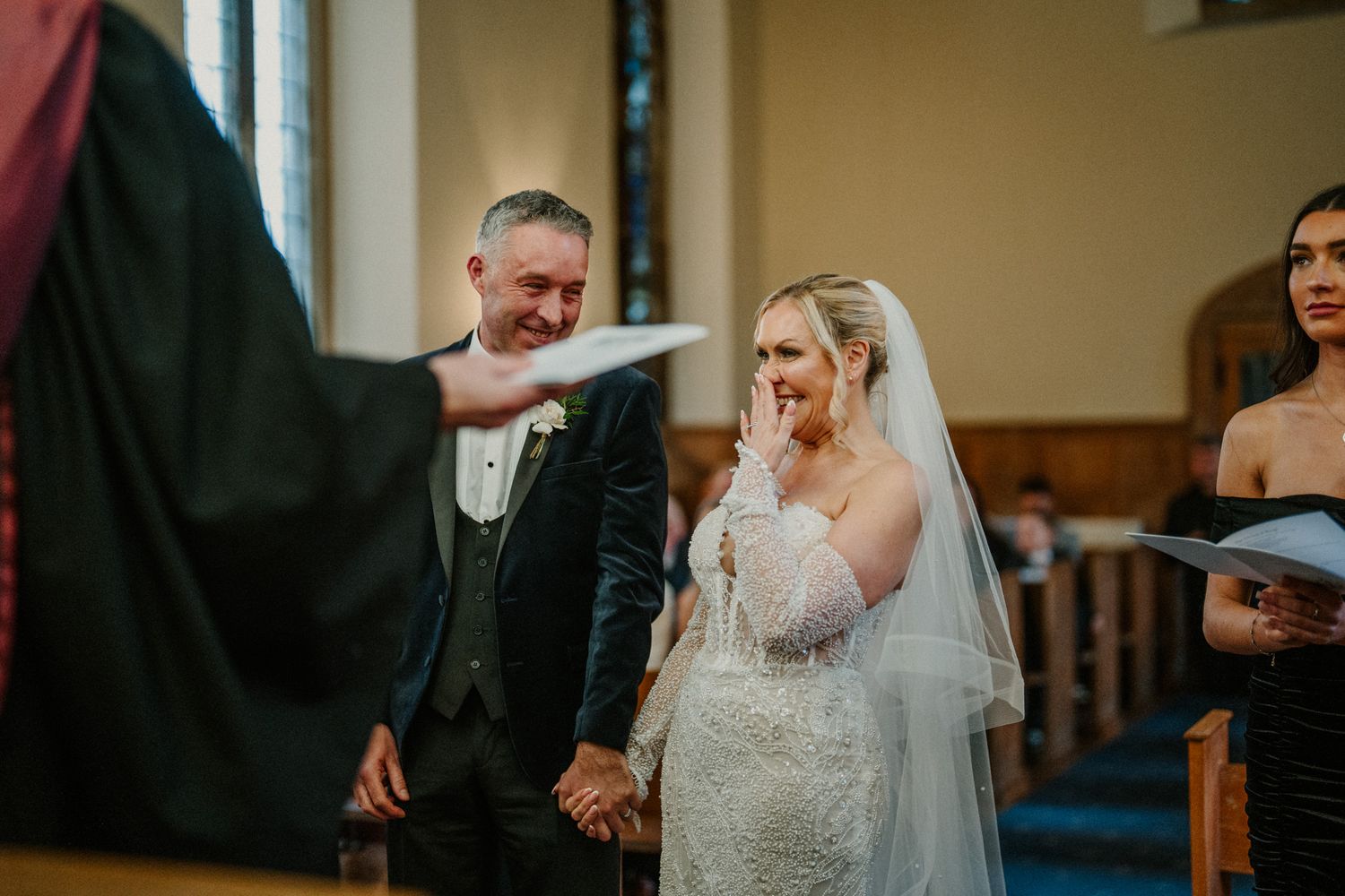 Wedding ceremony taking place inside a traditional church with warm lighting and wooden pews.