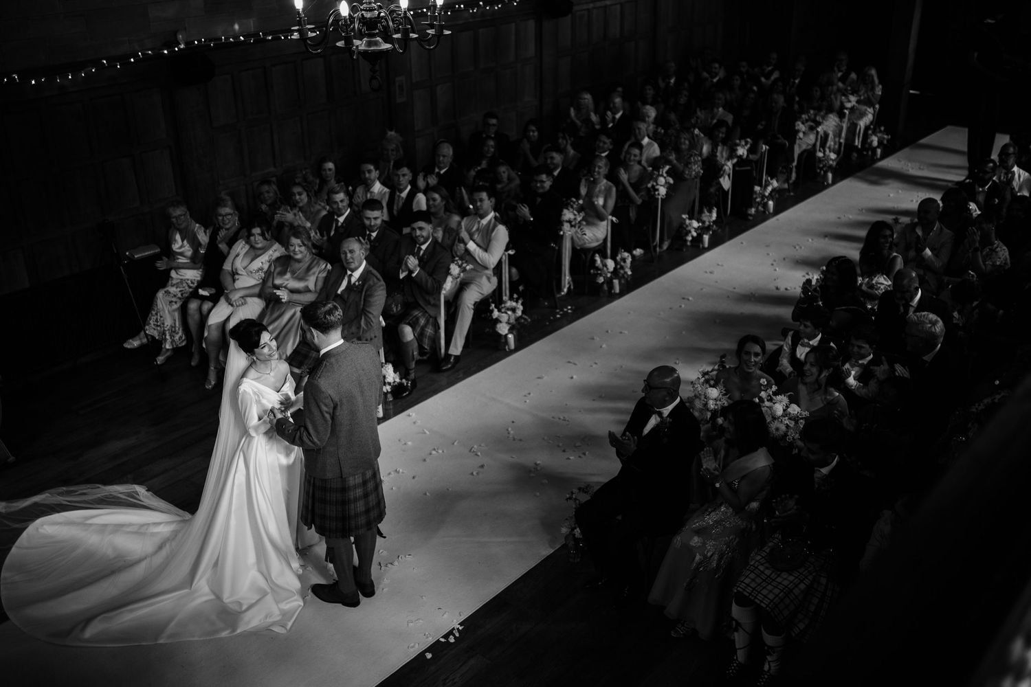 Black and white wedding ceremony photos showing a traditional church setting with elegant chandeliers.