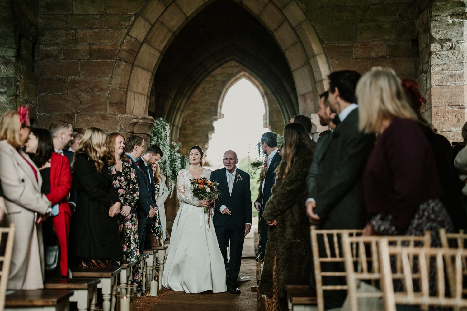 Interior of historic stone church decorated with flowers and wooden chairs for wedding ceremony.