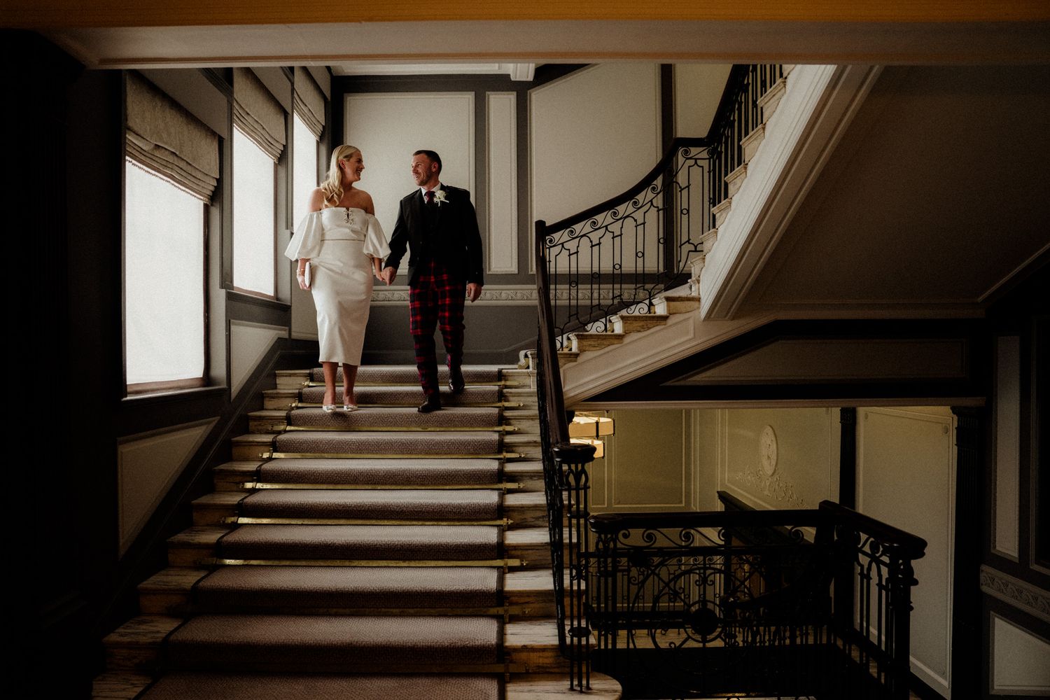 Dramatic staircase scene with black railings and white walls in wedding venue.