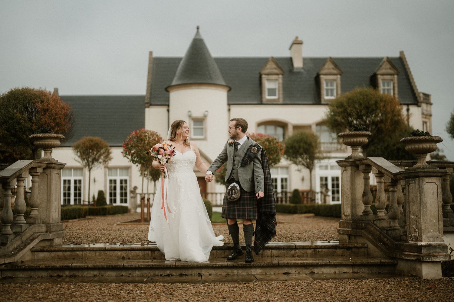A joyful wedding moment captured on stone steps leading to a stately manor house.