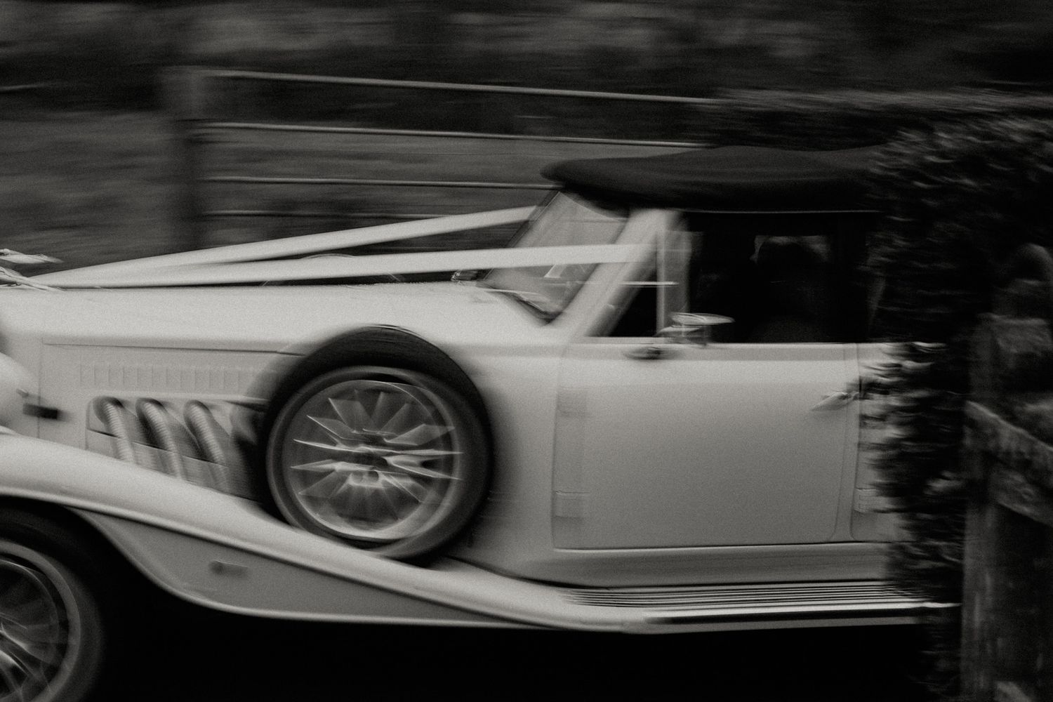 Classic white vintage wedding car in motion captured in black and white.