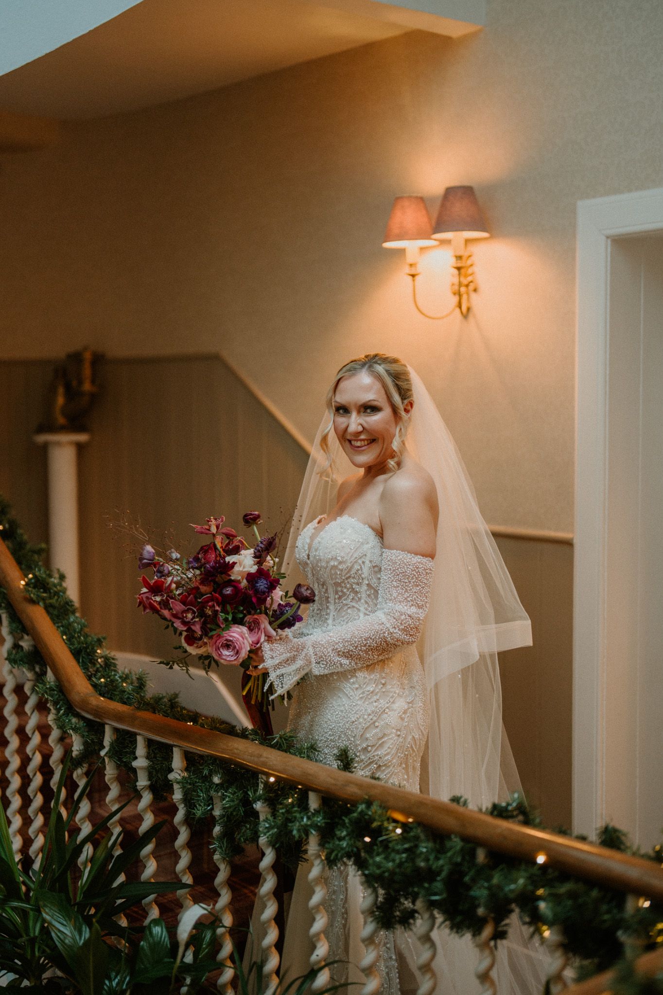 Ornate staircase decorated with greenery and soft lighting for a wedding celebration.