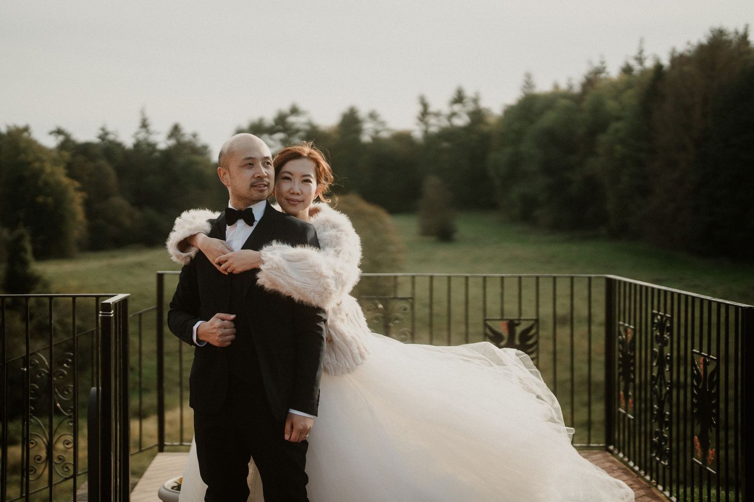 Newlyweds sharing intimate moment on stone terrace overlooking green landscape.
