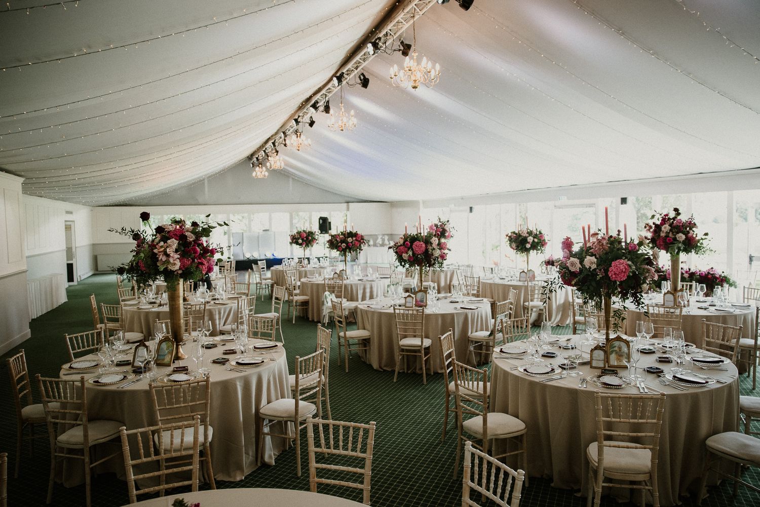 Wedding reception tent setup with round tables and elegant white draping.