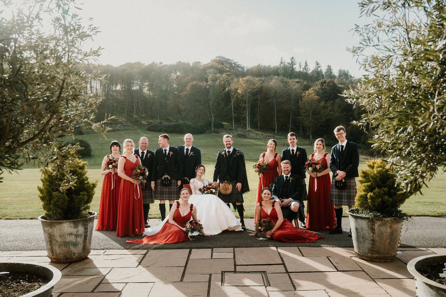 Wedding party poses outdoors on stone patio with scenic countryside views.