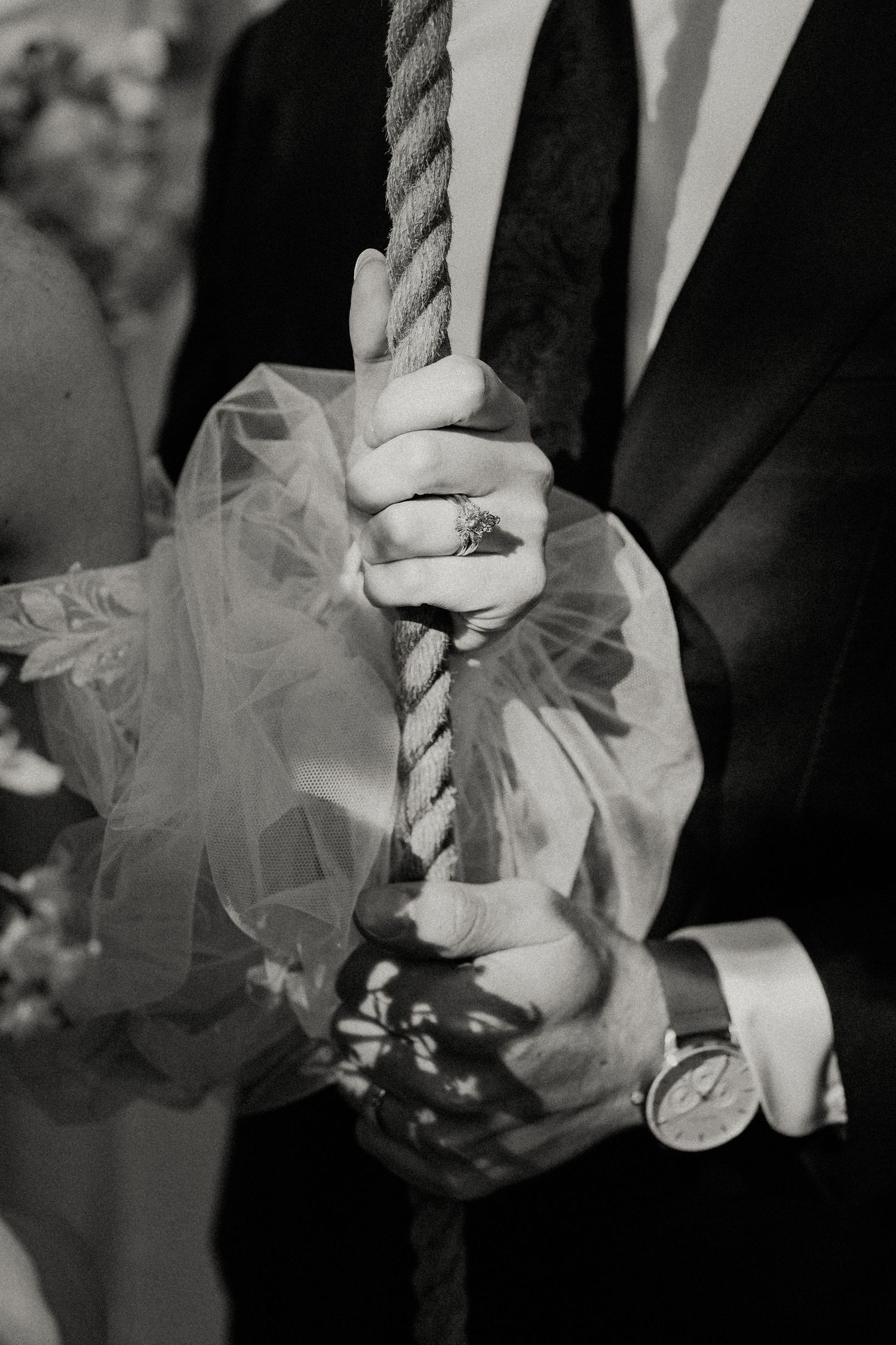 Black and white close-up of delicate tulle wedding dress details and hands.