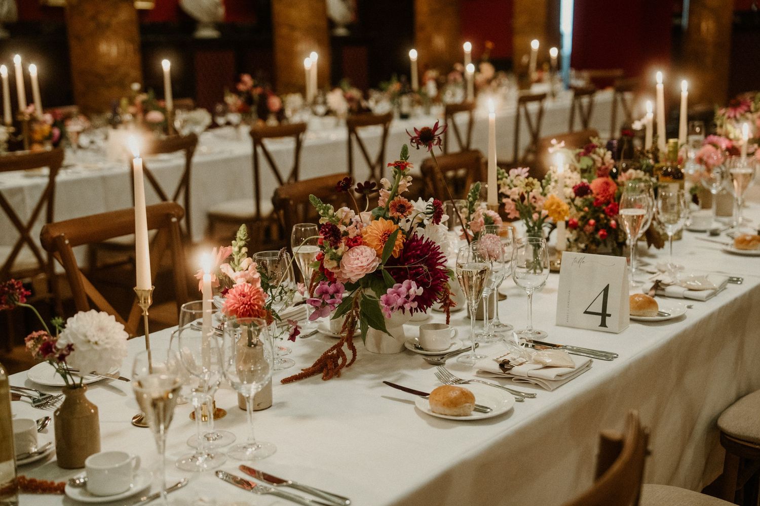 Elegant wedding reception table with floral centerpieces, candles and place settings.