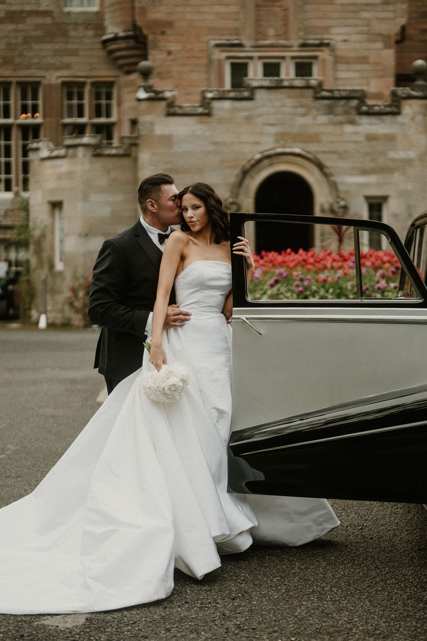 Romantic wedding portraits with classic car outside stone building.