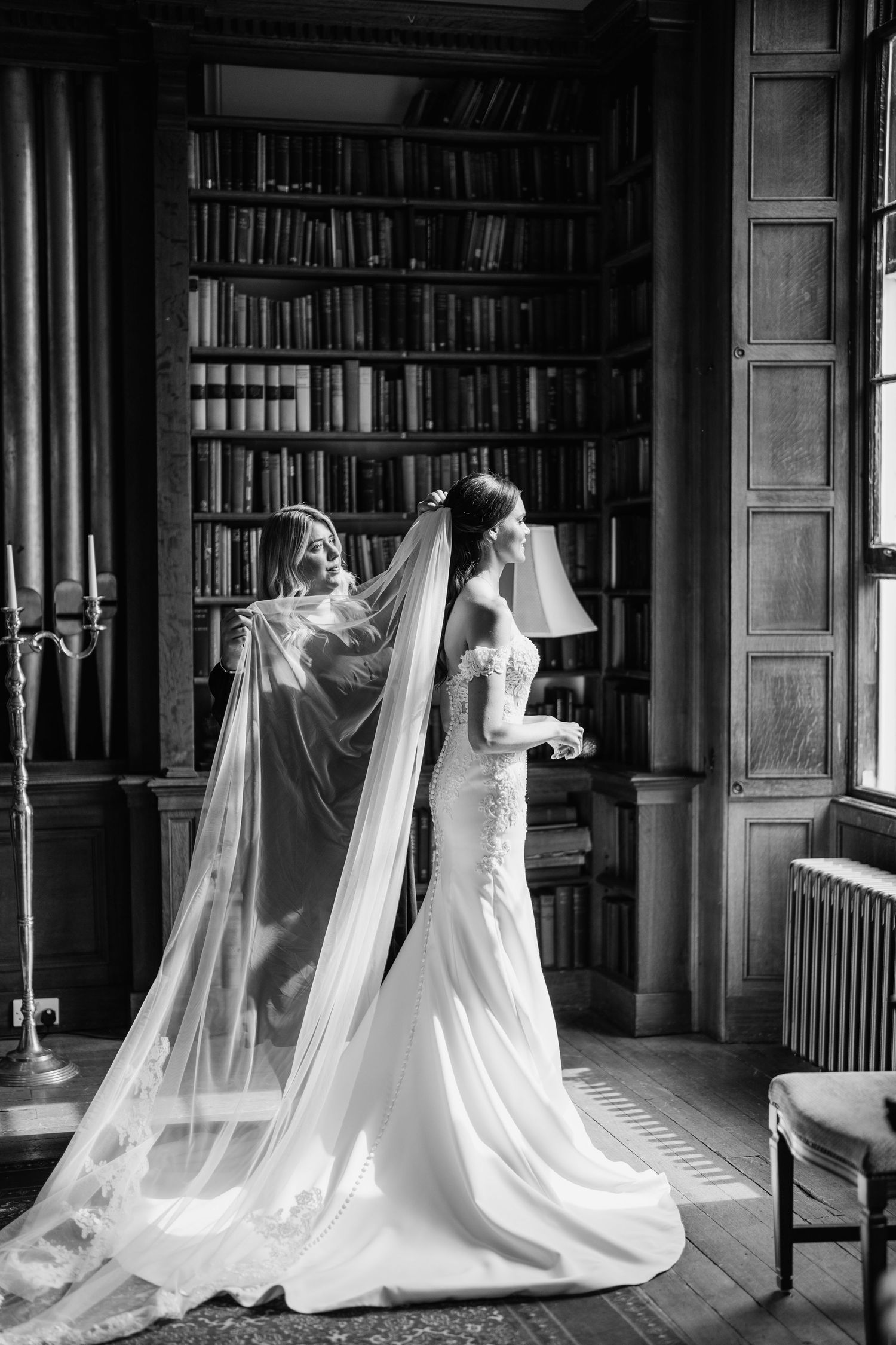 Wedding gowns with long veils arranged artistically in a grand library setting.