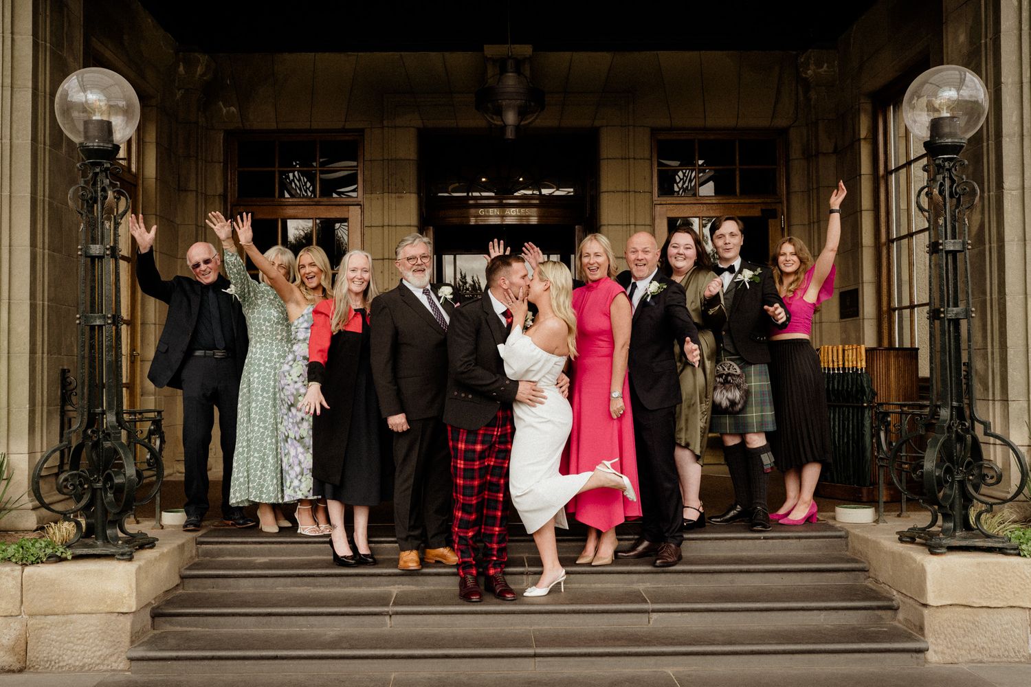 Large group photo of wedding guests on stone steps outside a historic building.