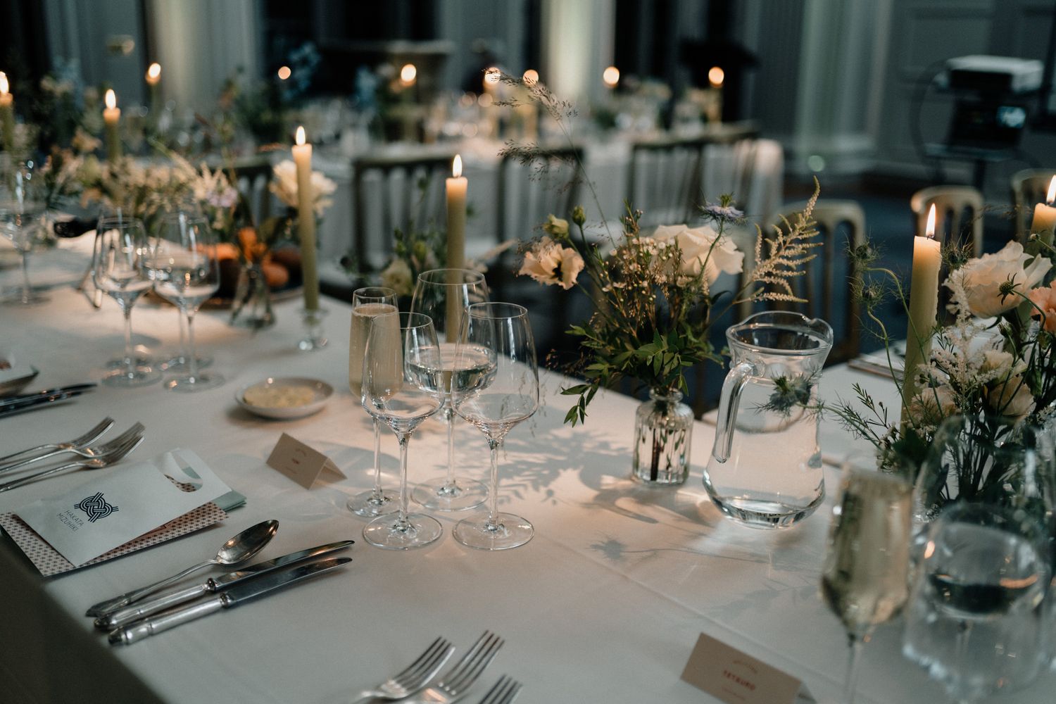 Elegant wedding reception tables set with glassware and floral centerpieces.