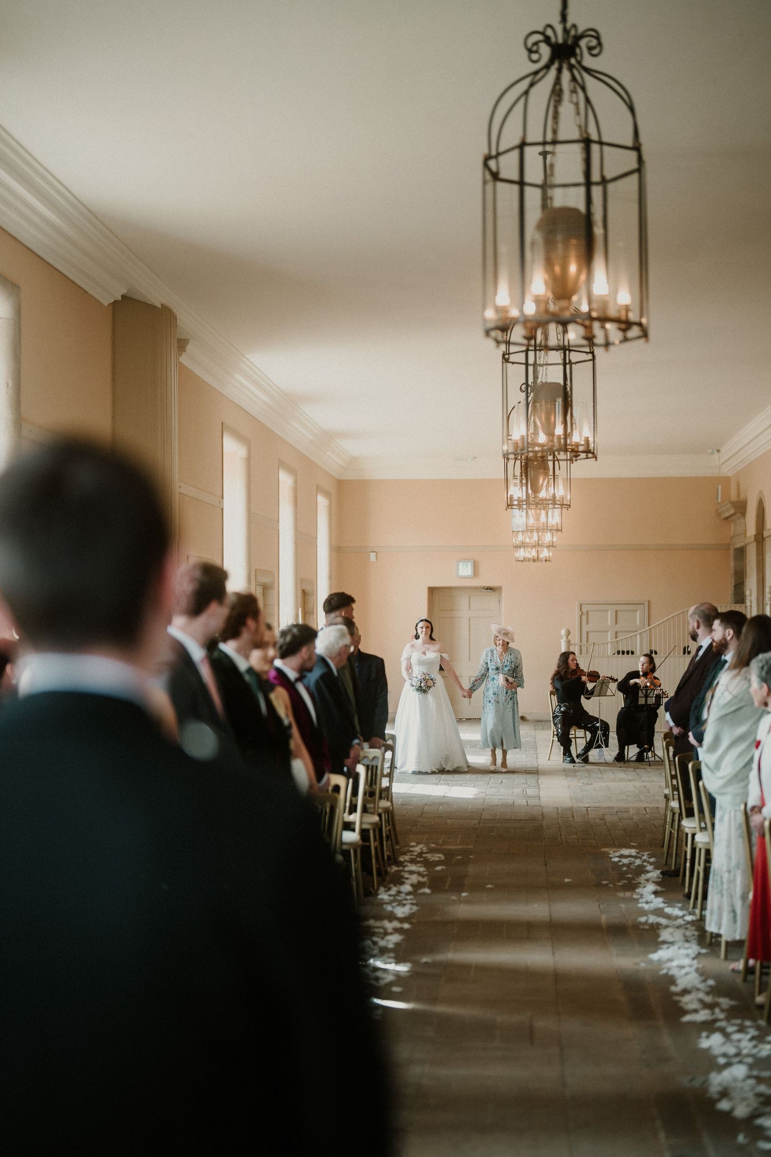 Elegant reception venue with wrought iron chandeliers and cream colored walls.