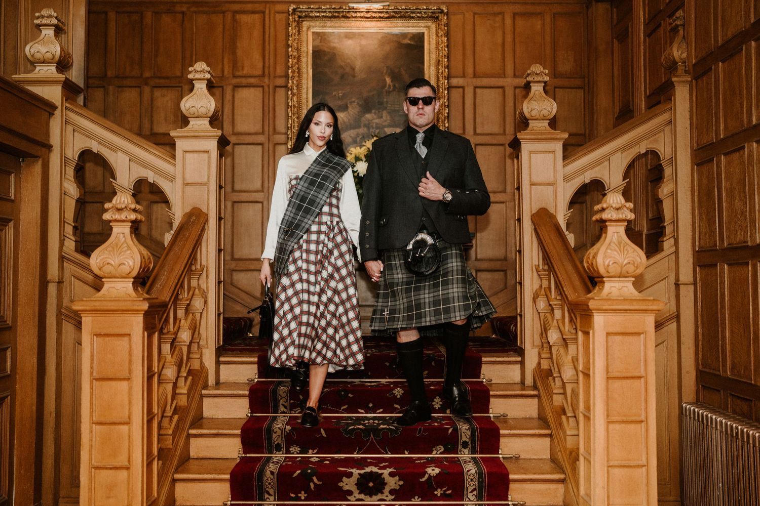 Guests gathered in an ornate wood-paneled hallway with decorative busts and architectural details.